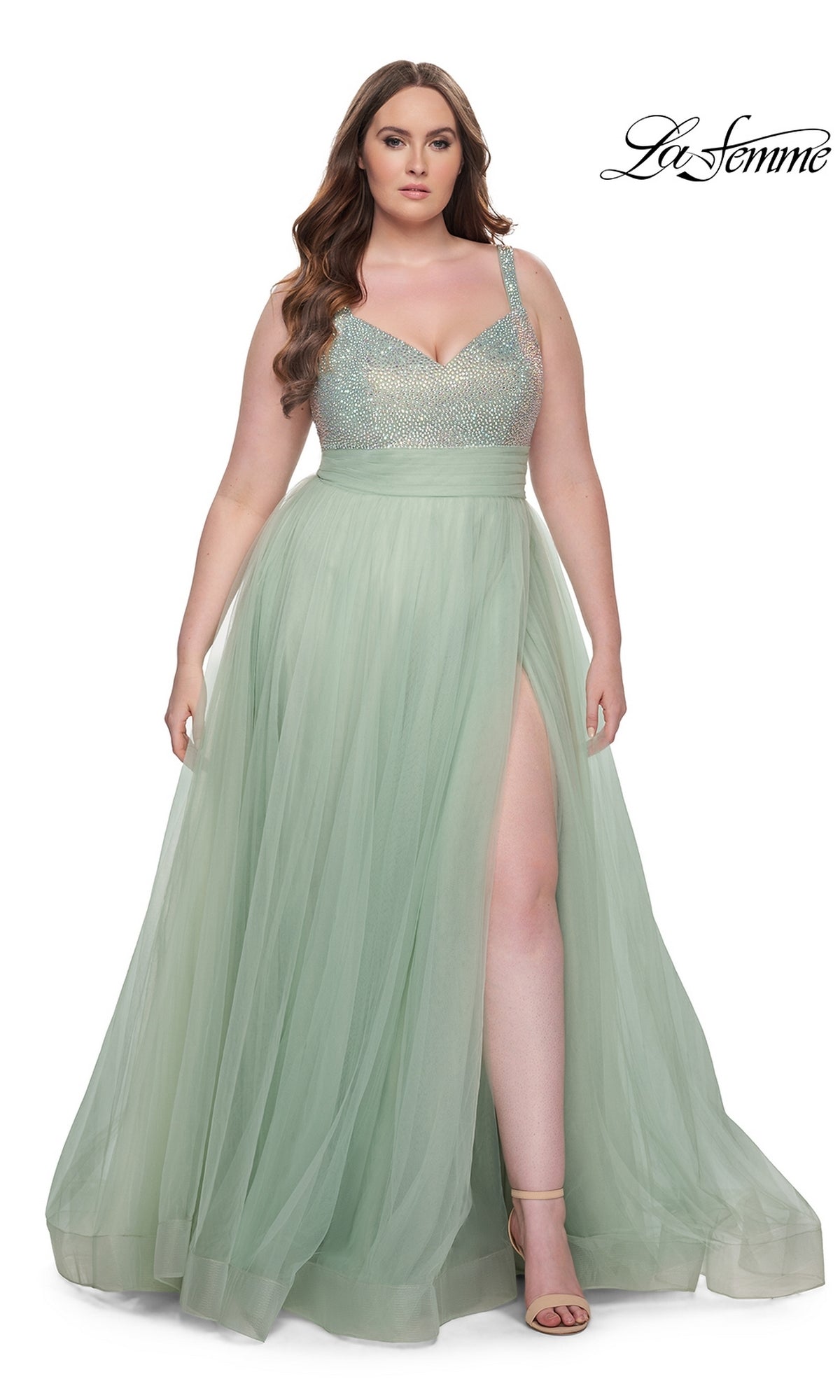 A woman models the La Femme Long Prom Dress 31251—a plus-size, light green gown with a beaded bodice, tulle skirt, and thigh-high slit—standing against a white background. The La Femme logo is displayed in the top right corner.